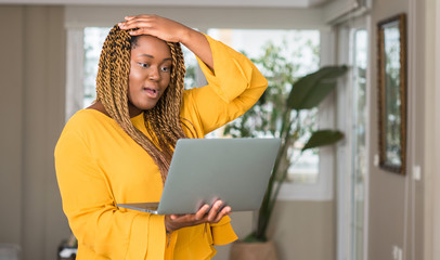 Poster - African american woman with laptop stressed with hand on head, shocked with shame and surprise face, angry and frustrated. Fear and upset for mistake.