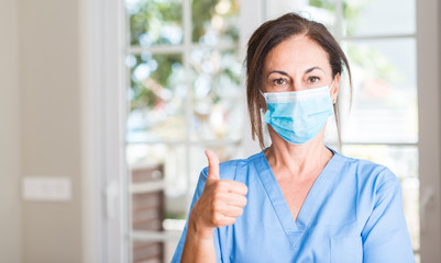 Middle aged doctor woman happy with big smile doing ok sign, thumb up with fingers, excellent sign