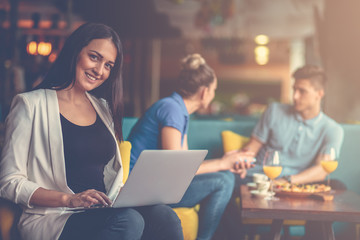 Wall Mural - Young female student is using laptop computer in cafe