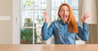 © Krakenimages.com - Redhead woman at home celebrating crazy and amazed for success with arms raised and open eyes screaming excited. Winner concept