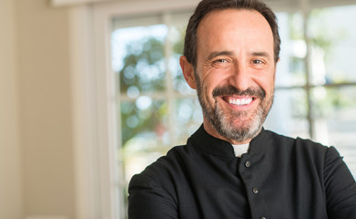 Christian priest man with a happy face standing and smiling with a confident smile showing teeth