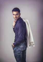 Wall Mural - Handsome young man in blue shirt and jeans posing on grey background in studio