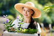 Portrait of cheerful young woman gardener with flowers in wooden box for sale in her shop