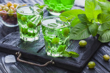 Green Gooseberry Cocktail With Ice And Fresh Mint On A Black Wooden Table. Refreshing Summer Drink