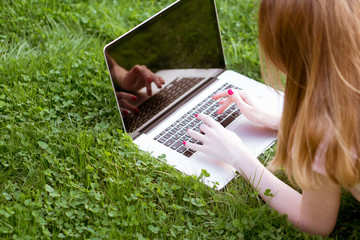 girl on the lawn typing on a laptop