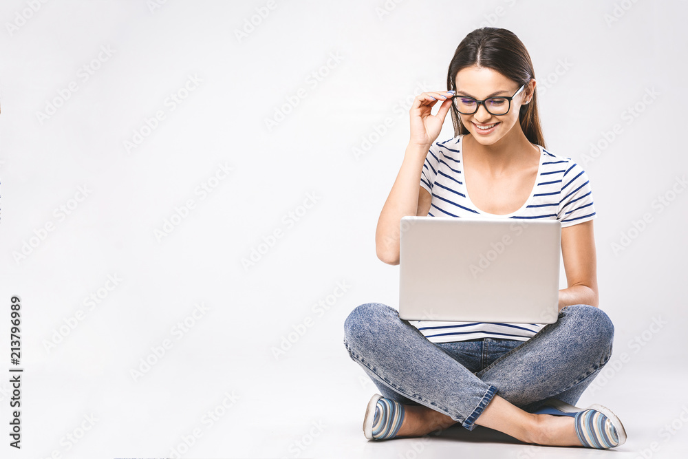 Business concept. Portrait of happy woman in casual sitting on floor in lotus pose and holding laptop isolated over white background. - obrazy, fototapety, plakaty 