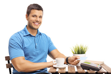 Wall Mural - Young man with a credit card sitting at a coffee table