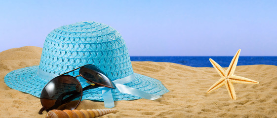 glasses, hat and sea shells on the sand