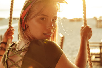 Poster - Young lady outdoors on the beach riding on swing.