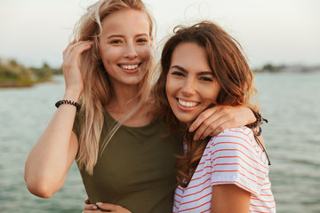 women friends hugging outdoors on the beach.