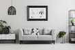 © Photographee.eu - Black industrial bookcase and a plant stand next to an upholstered sofa in a gray living room interior with place for a coffee table. Real photo