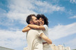 © LIGHTFIELD STUDIOS - low angle view of happy young multiracial couple hugging against blue sky