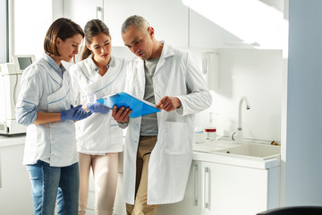 Medical dentist team in dental office discuss about practice and examining list of patients.