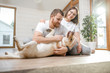 © rh2010 - Young lovely couple in white t-shirts playing with their dog sitting on the floor in the house