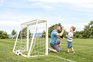 Man with child playing football outside on field