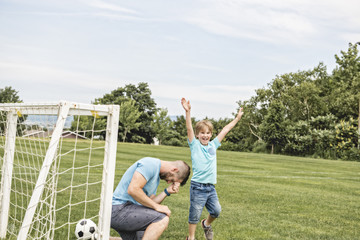 Wall Mural - Man with child playing football outside on field