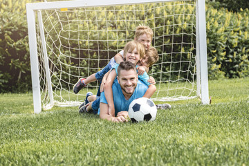 Wall Mural - Man with child playing football outside on field