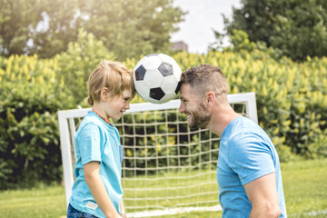 Wall Mural - Man with child playing football outside on field