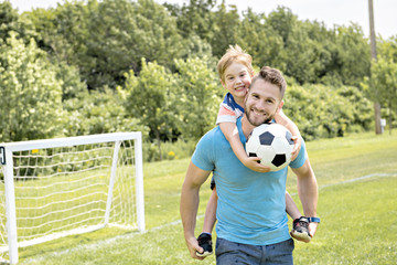 Wall Mural - Man with child playing football outside on field