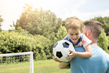 Wall Mural - Man with child playing football outside on field