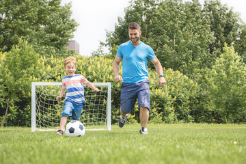 Wall Mural - Man with child playing football outside on field