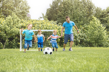 Wall Mural - Man with child playing football outside on field