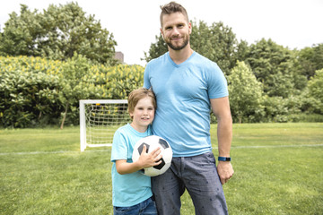 Wall Mural - Man with child playing football outside on field