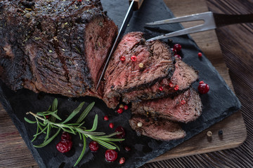 Appetizing roast beef with sauce and spices on a wooden table