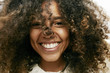 © Mint Images - Portrait of smiling young woman with brown curly hair, looking at camera.