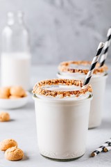 Sticker - Vanilla milkshake with crispy cookies in glass mason jar on gray background
