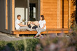 © rh2010 - Young lovely couple sitting with dog on the terrace on the backyard of their wooden country house