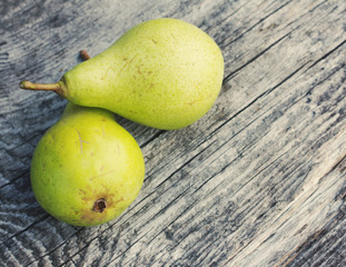 Two green ripe pears on an old wooden board, closeup