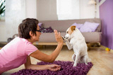 Fototapeta Koty - Frau spielt mit Hund im Wohnzimmer