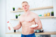 © satyrenko - Muscular man with a naked torso in the kitchen with milk and cottage cheese, the concept of a healthy diet. Athletic way of life.