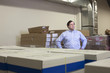 © ASHOK    SINHA - Business owner standing inside office warehouse with piles of business supplies around him