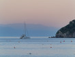 catamaran sailboat anchored next to small island   mountains in background