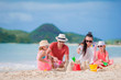© travnikovstudio - Family making sand castle on white beach on summer holidays