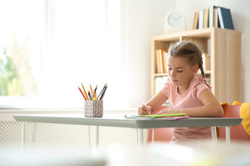 Cute little child doing assignment at desk in classroom. Elementary school