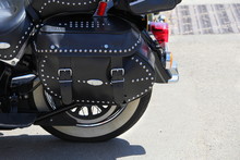 Close Up Of A Black Leather Strapped And Studded Motorcycle Pannier Or Bag, On A Sunny Day