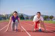 © blicsejo - Young sportive couple warming up legs before jogging on running track at sports stadium