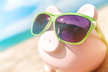 Wall Mural - Piggy bank with sunglasses on the beach