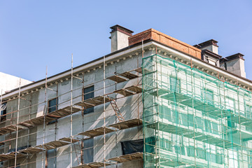 facade of a renovated building. scaffolding with green protective net