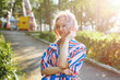 © Мария Балчугова - Bright summer image. The girl is blonde in a bright striped shirt dress walking in the amusement Park. Portrait of a woman on vacation. She's fooling around and having fun with the carousel.