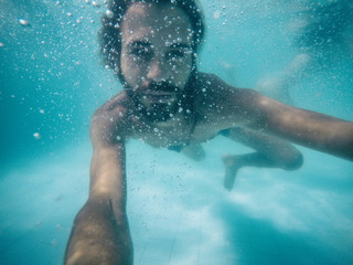  Attractive young man submerged in pool looking at camera