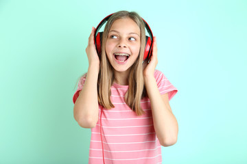 Wall Mural - Beautiful young girl with headphones on mint background