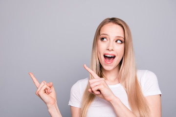 Portrait of young caucasian, charming, attractive gorgeous excited girl pointing showing up with two fingers. Isolated over grey background, copy space