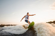 © fesenko - Active man riding on green wakesurf down the river waves
