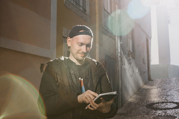 Wall Mural - A young male tourist on the street uses a tablet to look at an application with maps of the area or call a taxi or something else