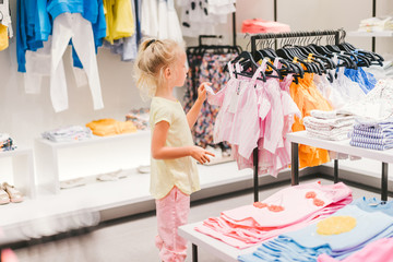 Wall Mural - selective focus of adorable little child choosing clothes in shop