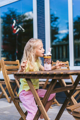 Wall Mural - selective focus of little child with closed eyes eating delicious dessert at table in cafe